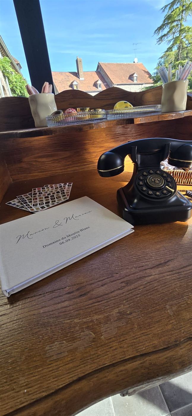 Téléphone livre d'or audio posé sur une table en bois