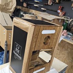 Borne photo en bois assemblée, flanc noir gravé du logo CJ BOX, dans l'atelier GEN3D
